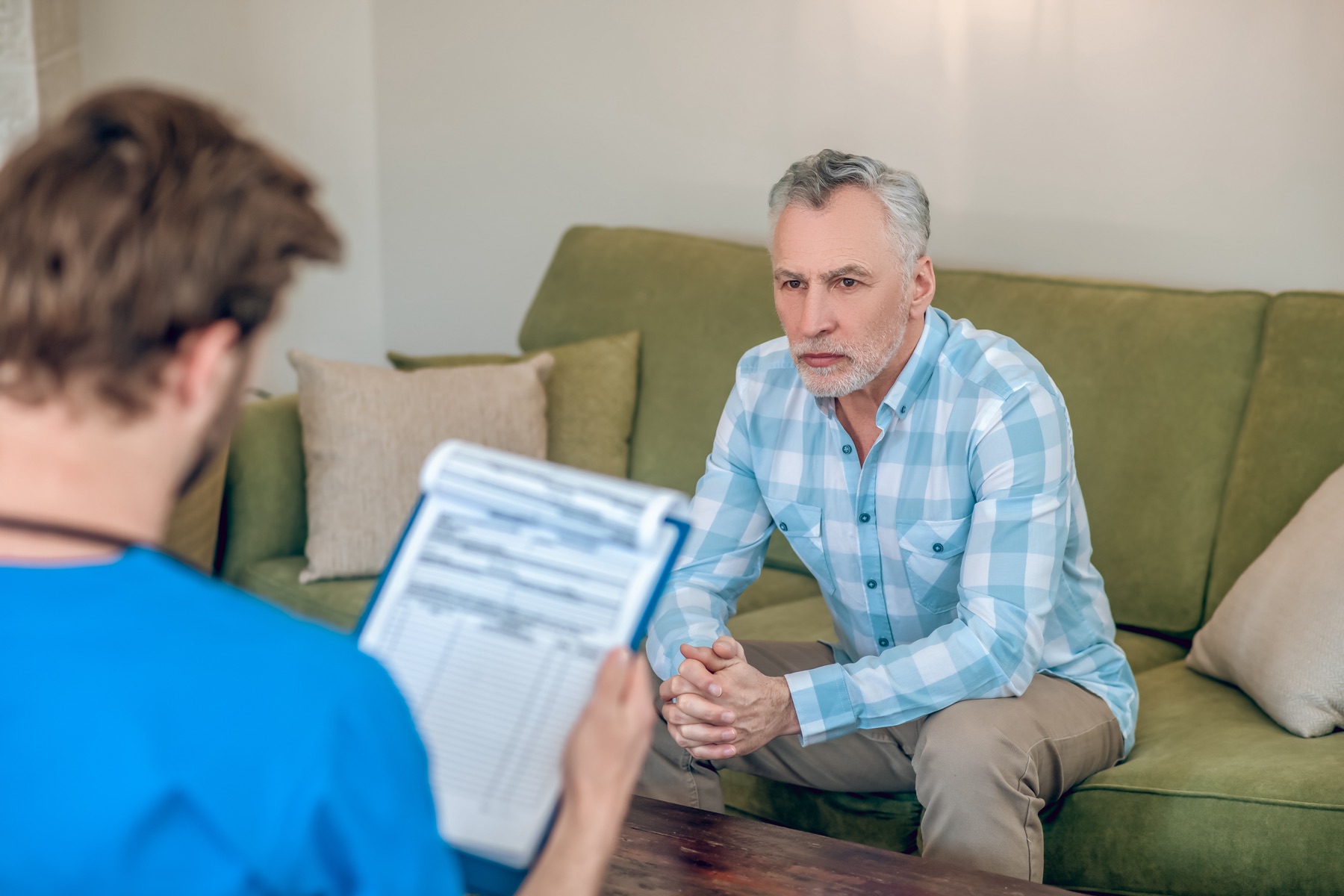 A man in conversation with a clinician holding a clipboard